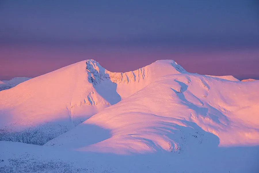 粉色晨光照亮连绵雪峰